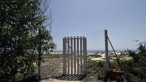 Une porte qui mène à une plage d’où l’on a une vue dégagée sur l’océan.