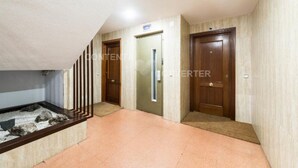 A hallway with a wooden staircase, a door with a sign, and a tiled floor.