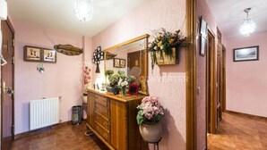 A hallway with a wooden cabinet, a mirror, and various decorations including framed pictures and flowers.