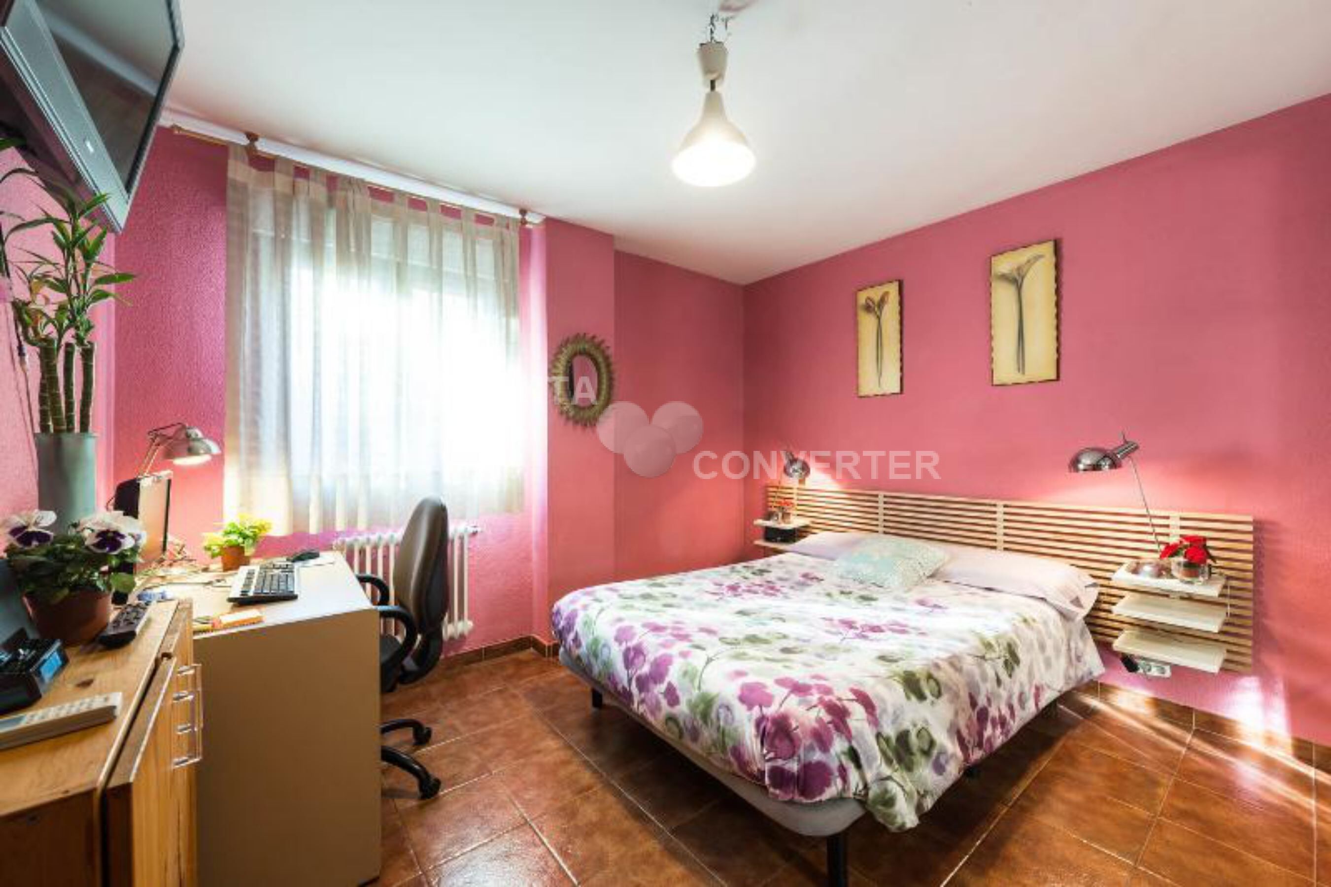 Un dormitorio con cama, escritorio, silla y radiador.