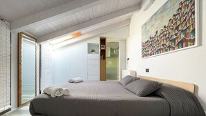 A bedroom with a bed, a painting, a door, and a window. - URG - Luxury penthouse in Catania Unesco centre (catania)