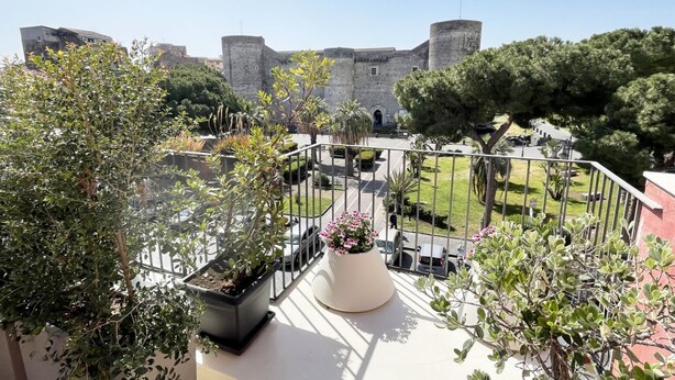 A balcony with potted plants and a view of a historic stone building. - URG - Luxury penthouse in Catania Unesco centre (catania)