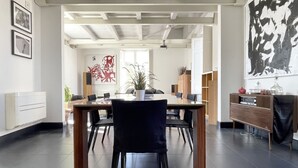 A modern dining area with a wooden table and chairs, a potted plant, and a large abstract painting on the wall. - URG - Luxury penthouse in Catania Unesco centre (catania)