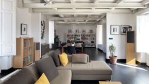 A modern living room with a sectional sofa, a bookshelf, and a dining area. - URG - Luxury penthouse in Catania Unesco centre (catania)