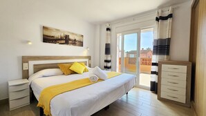 Una camera d'albergo con un letto, un comodino, una cassettiera e un balcone con tende.