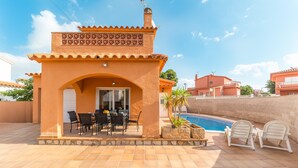 Una veranda coperta con tavolo e sedie, una piscina e un piccolo giardino.