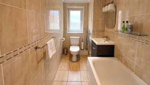 A modern bathroom with a bathtub, toilet, and sink. - Boutique Apartment on Royal Mile - Sleeps 3 (Edinburgh)
