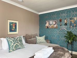 A bedroom with a bed, pillows, a framed picture, a map, and decorative items on the wall. - Boutique Apartment on Royal Mile - Sleeps 3 (Edinburgh)
