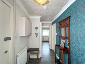 A hallway with a radiator, a bench, a door, and a wall-mounted light fixture. - Boutique Apartment on Royal Mile - Sleeps 3 (Edinburgh)
