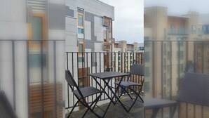 A balcony with a table and chairs, a modern building with patterned facade, and a view of neighboring buildings. - Boutique Apartment on Royal Mile - Sleeps 3 (Edinburgh)