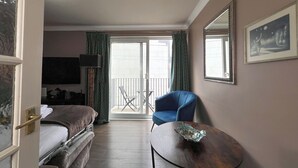A hotel room with a bed, a chair, a table, a balcony with a chair, and a large mirror. - Boutique Apartment on Royal Mile - Sleeps 3 (Edinburgh)