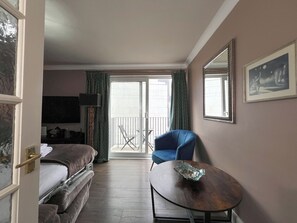 A hotel room with a bed, a chair, a table, a balcony with a chair, and a large mirror. - Boutique Apartment on Royal Mile - Sleeps 3 (Edinburgh)
