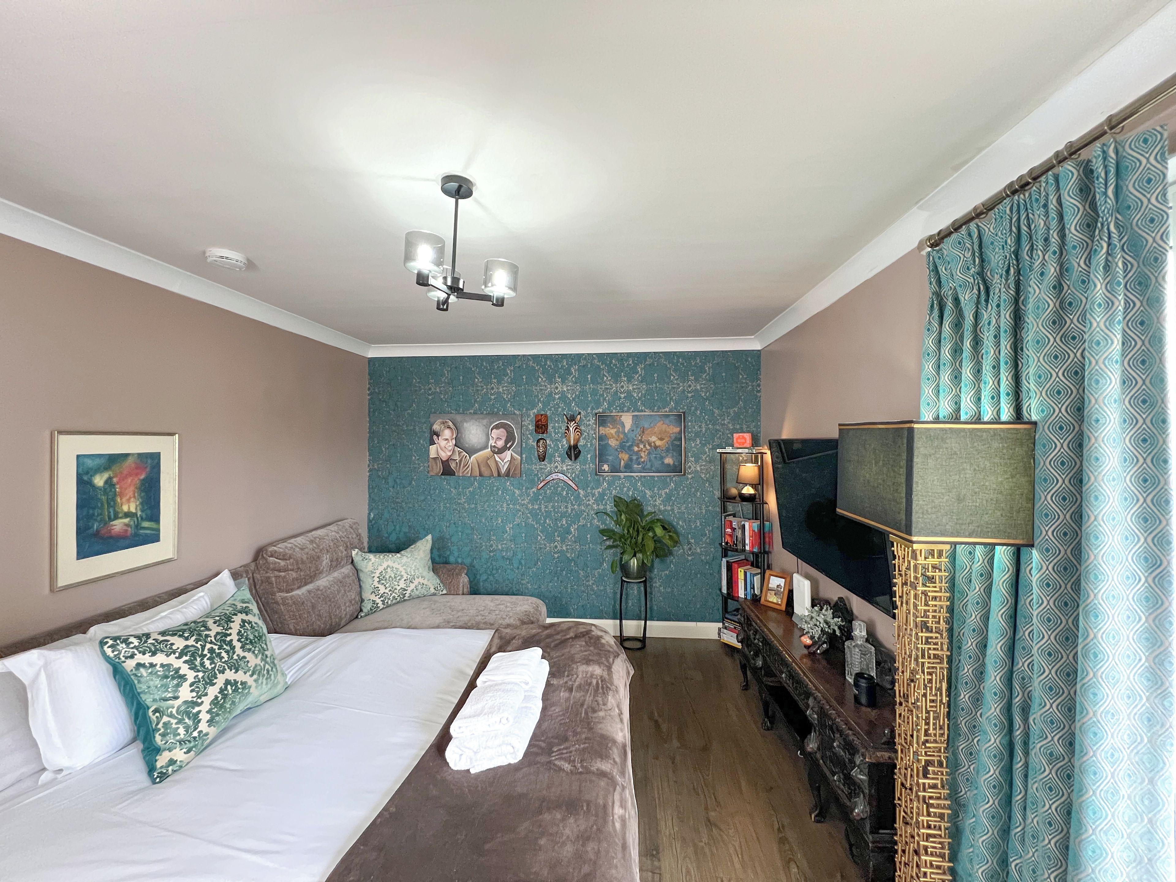 Een hotelkamer met een bed, een bureau, een televisie en een boekenplank.