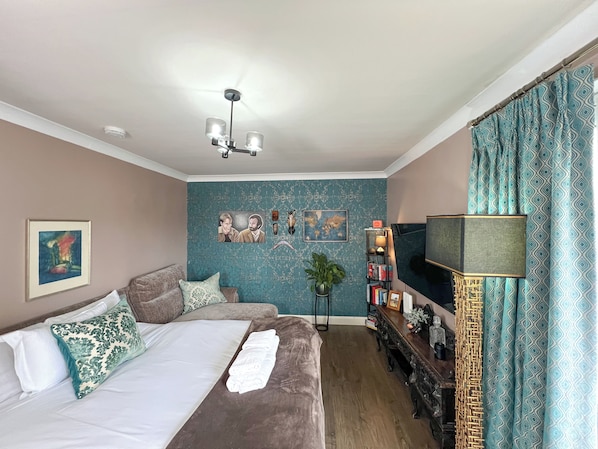 Una habitación de hotel con cama, escritorio, televisor y estantería.