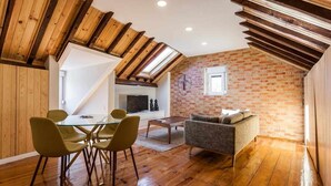 A loft-style room with a dining area, a sofa, and a TV. - Charming Flat with A/C & Terrace in Príncipe Real (Lisboa)