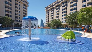 Una piscina con fuente de agua y tobogán verde.