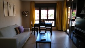 A living room with a sofa, a coffee table, a TV, and a dining area with chairs and a table. - COZY APARTMENT IN PALM MAR (arona)