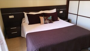 A neatly made bed with a dark headboard, a white pillow, and a decorative pillow with a floral pattern. - COZY APARTMENT IN PALM MAR (arona)