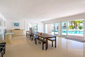A spacious kitchen with a long dining table, a glass cabinet, and a view of a swimming pool. - 2 POOLS, FOOTBALL PITCH, TENNIS COURT, CINEMA ROOM, GYM, BAR, PRIVATE CHEF (Poceirão)