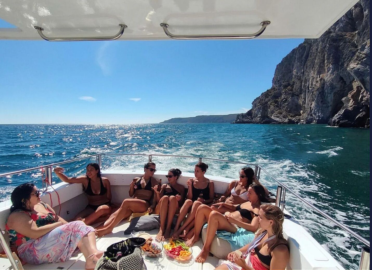 A group of people on a boat with a rocky coastline in the background.