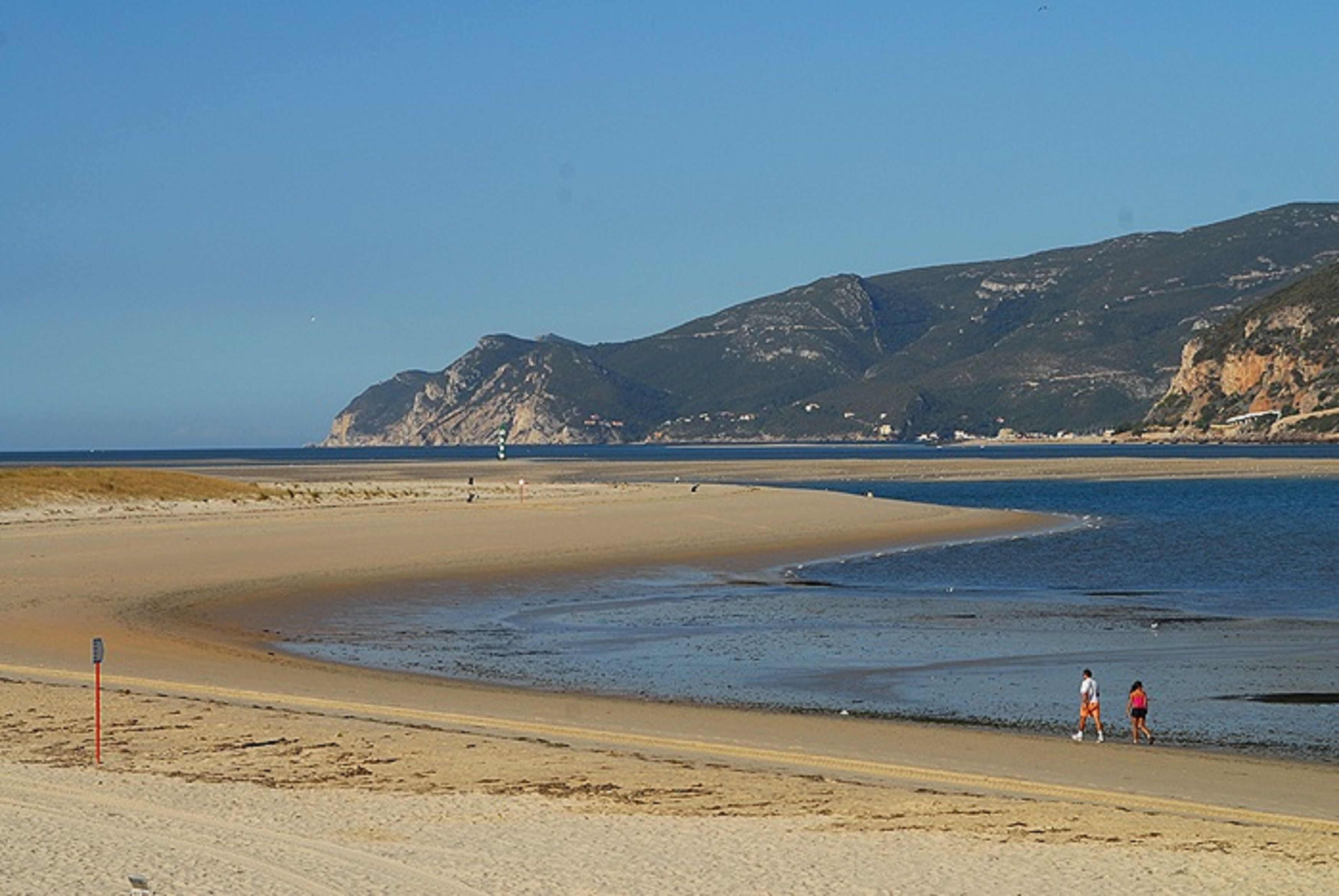 A beach with a clear view of the sea and distant mountains.