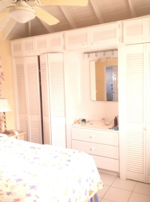 Un dormitorio con una cama, un aparador, un espejo y un ventilador de techo.