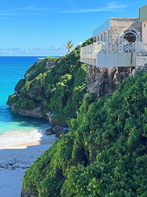 A coastal hotel with a view of the ocean and a beach.