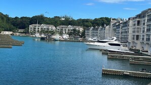 A marina with several yachts docked, surrounded by multi-story buildings with classical architecture.