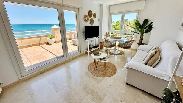 A spacious living room with a large sliding glass door leading to a balcony with a view of the ocean. - Sunrise 01 by homeprive (Denia)