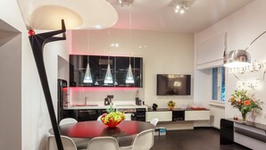 A modern kitchen with a dining area, featuring a large island, pendant lights, and a flat-screen TV. - New duplex apts in VATICAN - M + I (Roma)