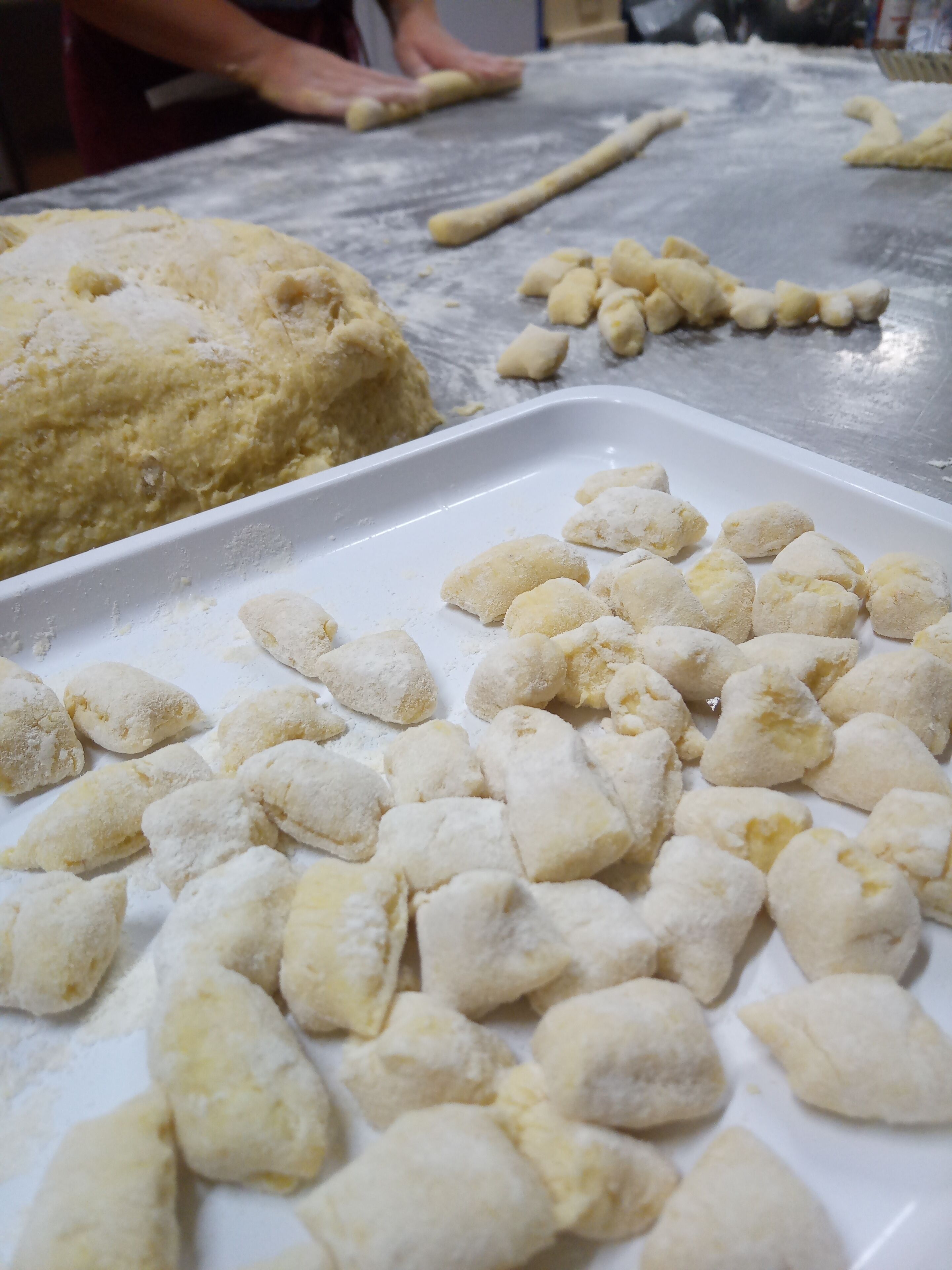 Una cocina con masa sobre la encimera y una bandeja para hornear con porciones de masa dadas forma.