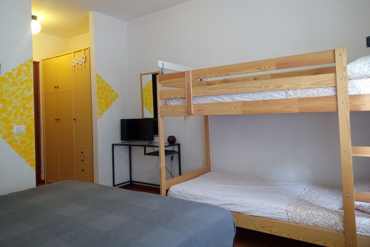 A bunk bed room with a desk and a wardrobe.