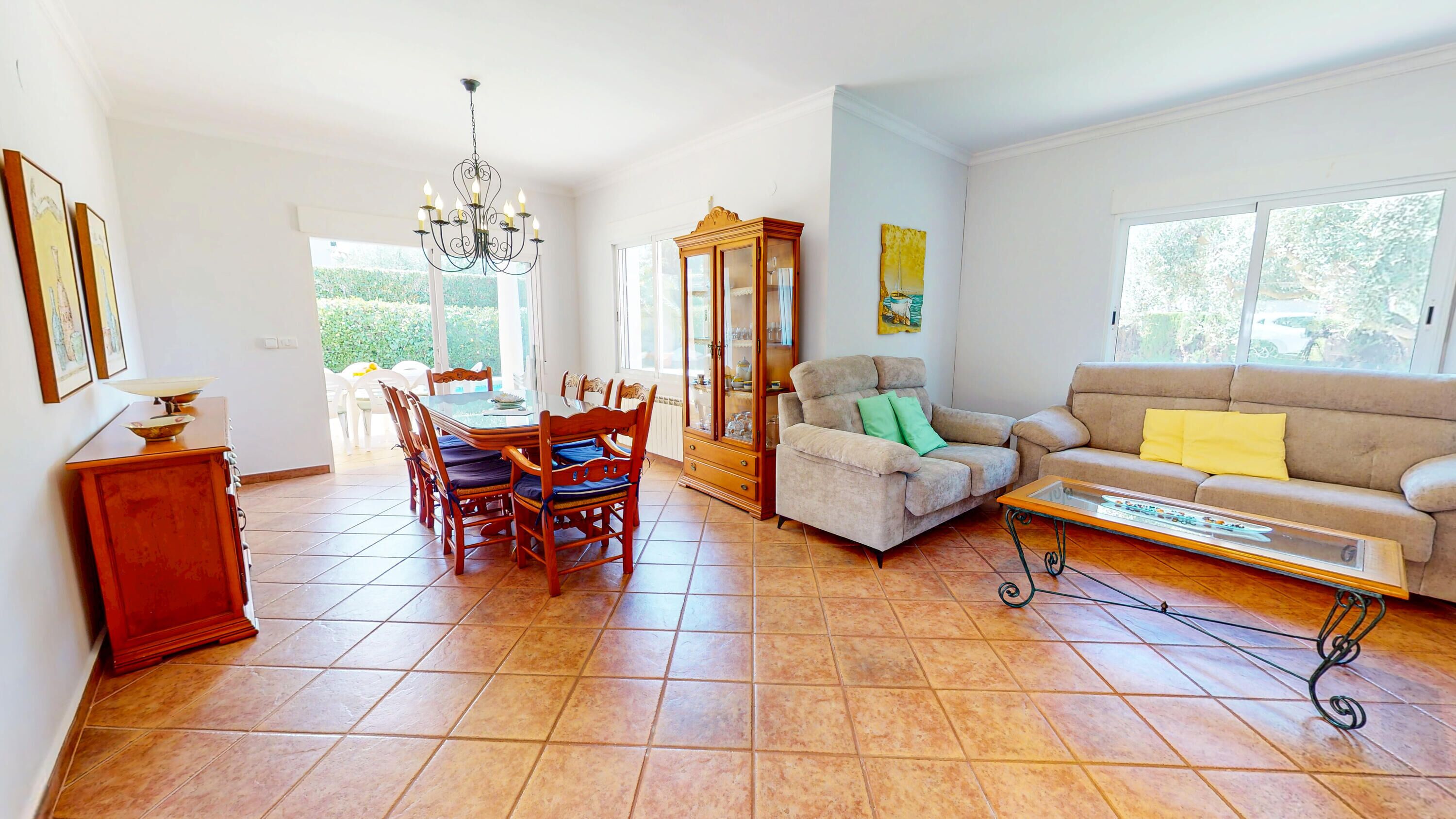 A spacious living room with a dining area, a sofa, a coffee table, and a chandelier.