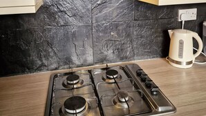 A kitchen with a gas stove, a kettle, and a modern backsplash. - Stay Norwich Apartments Trade Stay House (Norfolk)