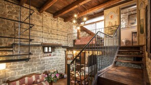 Ein rustikales Interieur mit Steinwänden, einer Holztreppe und einer gemütlichen Sitzecke.