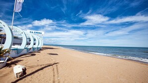 Une plage avec un panneau indiquant « CA CHEMA » et une structure aux couleurs bleu et blanc.