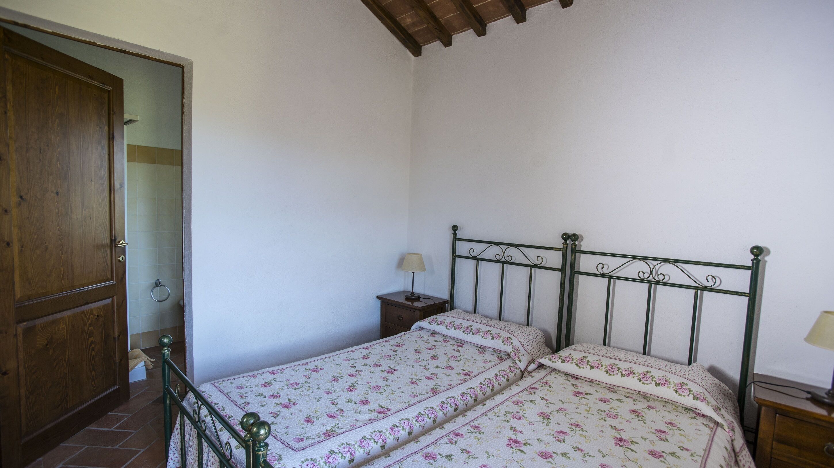 Een slaapkamer met een houten garderobe, een metalen bedframe en een nachtkastje met een lamp.