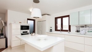 A modern kitchen with a central island, white cabinetry, and a large window.
