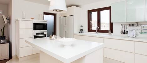 A modern kitchen with a central island, white cabinetry, and a large window.