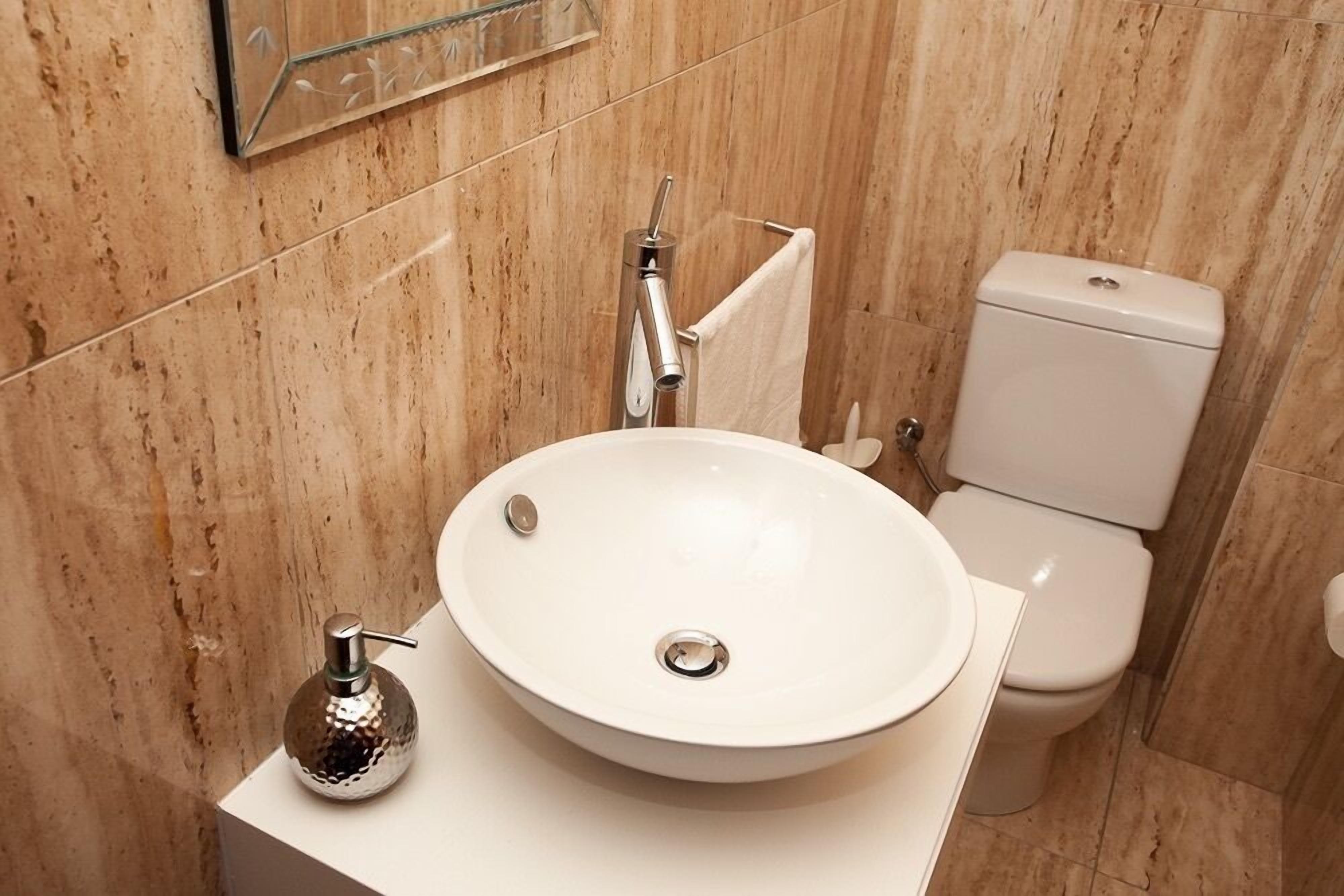 Ein Badezimmer mit Waschbecken, Spiegel, Toilette und Handtuchhalter.