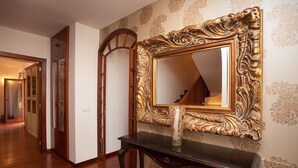 A hallway with a large ornate mirror, a console table, and patterned wallpaper.
