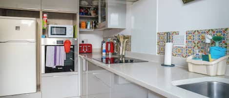 Een koelkast, een microgolfoven, kookgerei, borden en bestek