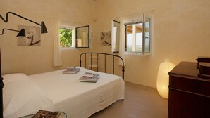 Une chambre à coucher avec un lit, des tables de chevet, une lampe et une fenêtre avec des rideaux.