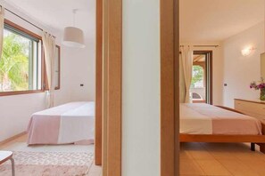 A bedroom with two beds, a wooden floor, and a window with curtains. - Apartament 350m from the sea - two verandas - parking - air conditioning (Specchiolla)
