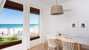Une pièce comprenant une table à manger, des chaises, un luminaire suspendu, une fenêtre donnant sur la mer et un climatiseur fixé au mur.