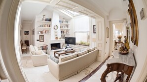 Una sala de estar amplia con chimenea, un sofá, un televisor y una estantería.