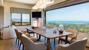 A modern dining area with a wooden table and chairs, a television, and a view of the landscape. - Lux Villa★SPA & Tennis★Jacuzzi & Indoor Pool★BBQ & Gym (Xirokampi)