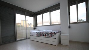 Un dormitorio con cama, una mesita de noche y ventana con vistas a edificios.