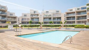 Un moderno edificio de apartamentos con piscina, balcones y mobiliario exterior.
