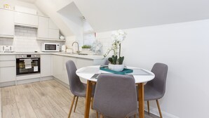 A modern kitchen with white cabinets, a microwave, an oven, and a dining area with a round table and four chairs. - 1 Bedroom City Centre Holiday home (York)